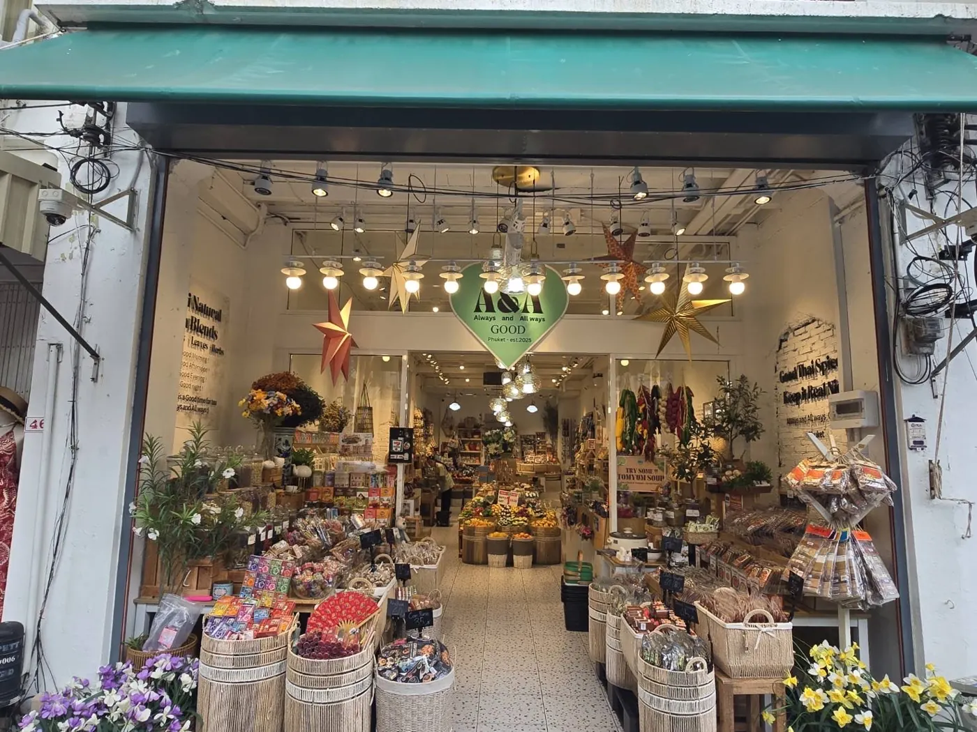 Entrance of A&A GOOD with baskets of Thai products and hanging star lanterns