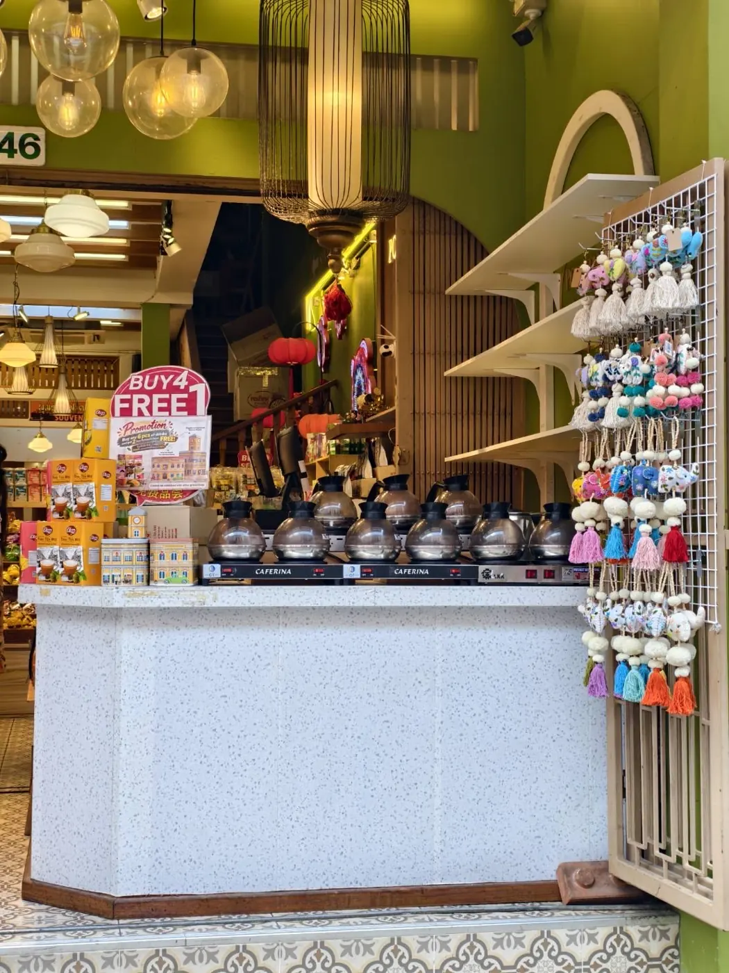 Front counter at Pornthip Old Town with Thai tea boxes, Phuket tin boxes and tassel keychains